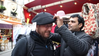 Il reporter da RTR avant in stand da via nua ch'i vegn vendì tastgas e chapès. In marchadant metta si a Stefan Dobler in beret.
