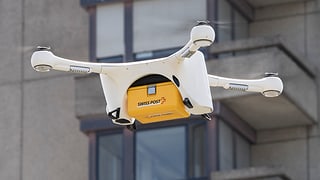 ina drona en l'aria cun in pachet da la Posta Svizra