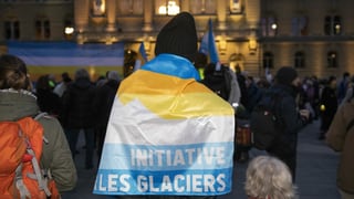 Persuna cun bandiera da iniziativa da glatschers sin plazza federala Berna.