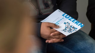 In requirent d'asil anonimisà cun ina broschura dal chantun Luzerna.