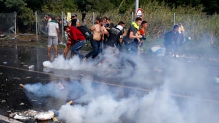 Fugitivs che scappan suenter che la polizia ha duvrà gas lacrimogen e chanuns d'aua cunter els. 