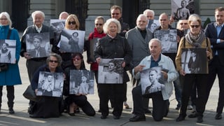 Intginas senioras e seniors stattan avant la chasa federala e mussan fotografias.