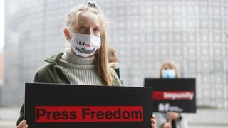 purtret d'ina giuvna dunna che tegna in placat enta maun durant ina demonstraziun, quel ha scrit si per englais «press freedom» «libertad da pressa».