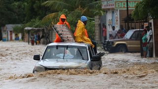 Las devastaziuns a Leogane en il Haiti èn enormas. In auto cun si duas persunas ermprova da traversar ina via inundada. 
