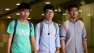 Trais giuvens asiats bandunan la dretgira a Hongkong. 