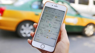In maun che tegna in telefonin cun avert l'app d'Uber. En il fund in taxi. In maun che tegna in telefonin cun avert l'app d'Uber. En il fund in taxi.