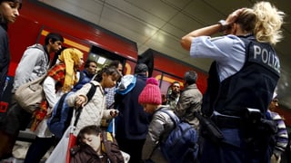 fugitivs vulan entrar en in tren, ina policista observa la situaziun