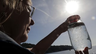 Dunna cun in glas cun aua enta maun. L'aua ha en particlas da plastic.