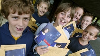 Uffants che tegnan prospects da la fundaziun Pro Juventute.