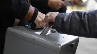 Urna da votaziu e maun che bitta en cedels.