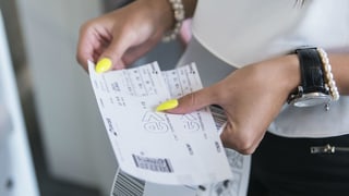 Purtret d'ina dunna che tegna enta maun dus tickets da sgular. 