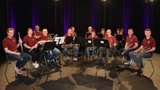 Die Blaskapelle Blaženka sitzend in Jeans und dunkelrotem T-Shirt