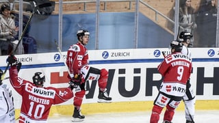 Purtret da giugaders da hockey che sa legran e tegnan en l'aria la fista. 