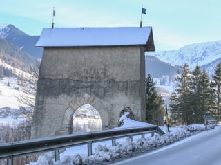 La porta da Porclas, in mir cun tetg nua che la via veglia manava atras.