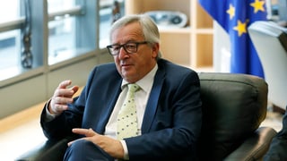 Juncker en ses biro a Brüssel davant ina badniera da l'UE.