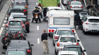 autos e töfs stattan en colonna, singulas persunas stattan sin la via