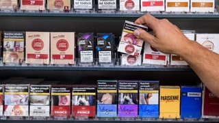 Purtret d'in regal cun cigarettas ed in maun che piglia or in pachet. 