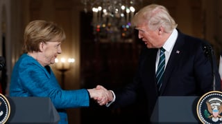 Purtret da Merkel e Trump che dattan il maun in a l'auter. 