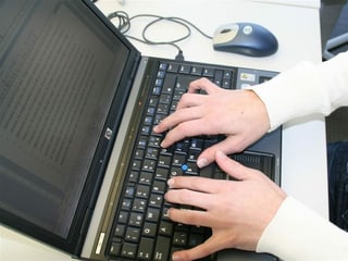 Ina persuna che scriva sinil laptop.