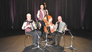 Ländlerkapelle Just/Meierhans/Haueter/Schmid, zu dritt, zwei Handorgeln und eine Bassgeige, alle mit schwarzer Hose, weissem Hemd und dunkelroter Wester