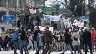 Purtret da persunas che demonstreschan a Berna. Els tegnan si transparents e tavlas cun scrit si diversas parolas. 