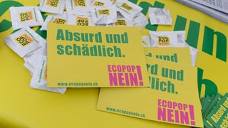 Placats mellens cun scrittira verda e rosa cunter l’iniziativa d’Ecopop cun il text Absurd und schädlich.