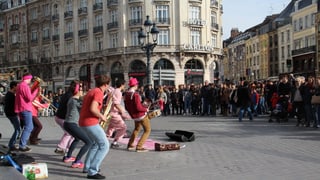 Students che fan musica sin las plazzas da Lille.