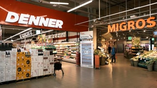 La foto mussa duas entradas da butias: da vart sanestra l'entrada dal Denner e da vart dretga l'entrada da la Migros