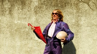 Helge Schneider cun in parisol ed ina chapellina enta maun. Helge Schneider cun in parisol ed ina chapellina enta maun.