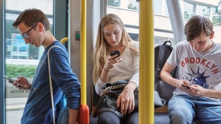 Giuvenils cun telefonin en in bus u tram. 