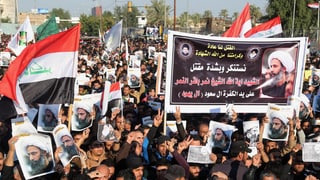 Fulla da glieud che demonstrescha cun plactats dal spiritual Nimr al-Nimr e bandieras da l'Irak.