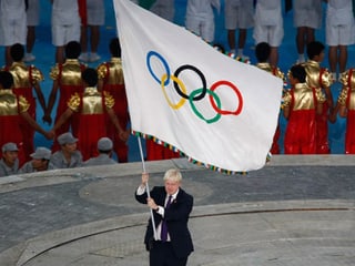 La bandiera olimpica vegn purtada en il stadion.