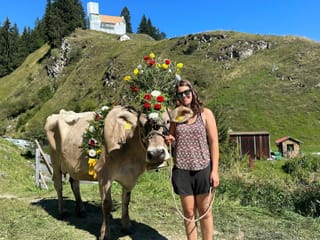 Junge Frau mit Kuh und Blumenkranz in der Natur