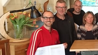 Marc Woodlit (giacca cotschna) cun decleraziun d'intenziun suttascritta. Marc Woodlit (giacca cotschna) cun decleraziun d'intenziun suttascritta.