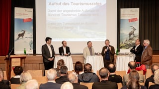 Arranschament cun public e davantvart in podi cun umens en discussiuns.