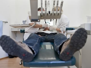 In dentist ed ina assistenta controlleschan ils dents dad in pazient.