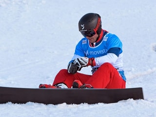 Nevin Galmarini che sesa cun ses snowboard en la naiv. Nevin Galmarini che sesa cun ses snowboard en la naiv.