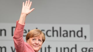 La chanceliera Angela Merkel salida giu d'ina tribuna a chaschun d'ina occurrenza en il cumbat electoral.