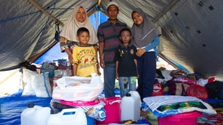 Famiglia da l'Indonesia en tenda cun rauba ord donaziuns. 