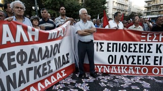 persunas che protestan cunter la povradad, dus placat cun scrittira greca