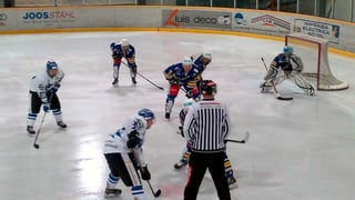 Giugaders da hockey ed in arbiter en acziun.