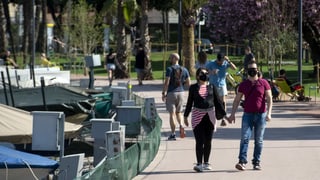 In perin cun mascras da protecziun che spassegia sper il Lai da Lugano.