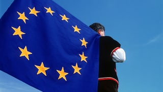 um cun vestgì tradiziunal porta ina bandiera da l'UE