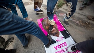Persunas che passan sin in placat d'elecziun en il Haiti.