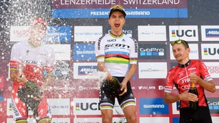 Nino Schurter giubilescha sin il podest a Lai cun sprizzar enturn ord ina butteglia champagner.