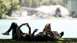 Purtret da duas persunas che giaschan sin in prà dasper il lai. 