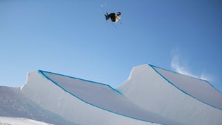 Sut davant dus grandas schanzas da saglir, sur en il tschiel blau in skiunz da freestyle che sgola e fa ses tricks.