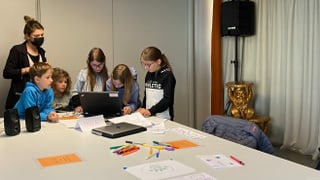 Tschintg uffants sesan vi dad in laptop per scriver in gieu auditiv. La manadra dal curs, Anna Fierz, è davostier e sustegn ils uffants.