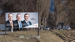 Purtret d'in placat cun ils trais candidats. 