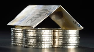Maletg simbolic - ina chasa ch'è fatga or da daners - pitgas da tschintg francs cun in tetg d'ina bancnota da 200